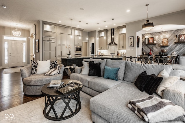 living room with ornamental molding, dark hardwood / wood-style flooring, sink, and a notable chandelier