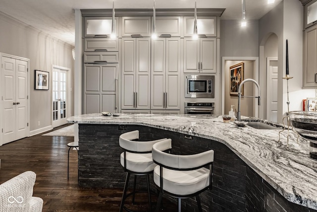 kitchen with sink, a breakfast bar area, dark hardwood / wood-style floors, pendant lighting, and stainless steel appliances