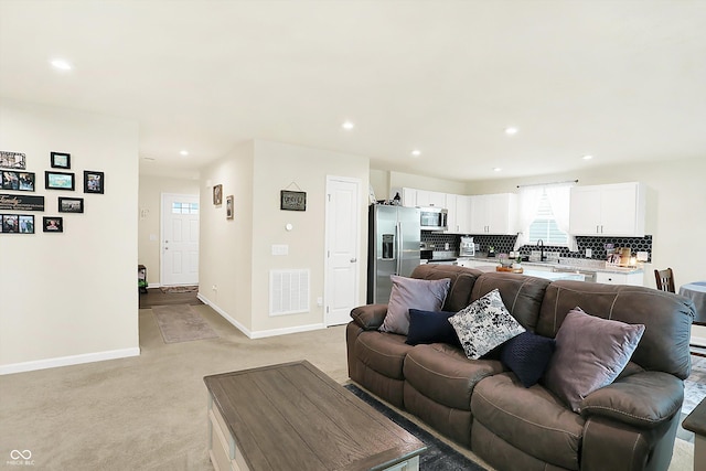 living room with light colored carpet and sink