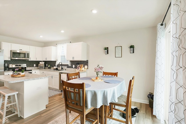 kitchen with appliances with stainless steel finishes, a center island, sink, and white cabinets