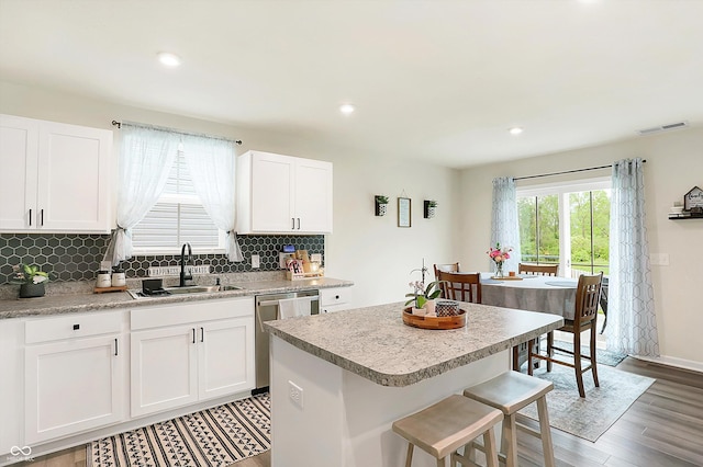 kitchen featuring sink, hardwood / wood-style flooring, dishwasher, white cabinets, and a kitchen island