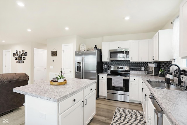 kitchen featuring sink, white cabinetry, backsplash, stainless steel appliances, and a kitchen island