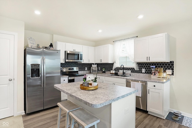 kitchen featuring a kitchen bar, sink, a center island, appliances with stainless steel finishes, and white cabinets