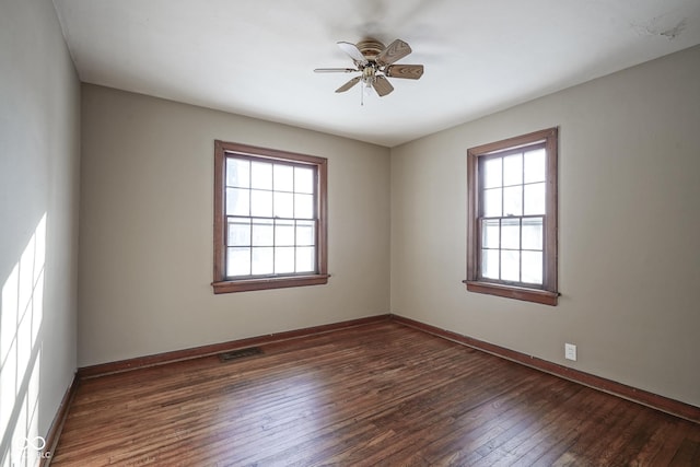 spare room featuring ceiling fan, dark wood-type flooring, and a healthy amount of sunlight