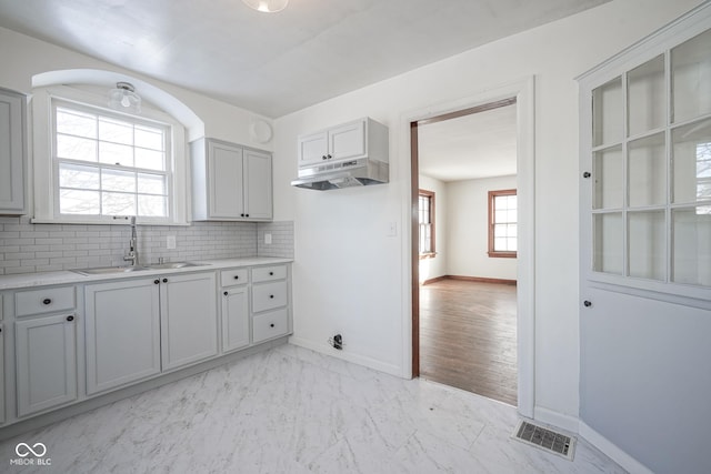 kitchen with gray cabinets, sink, and decorative backsplash