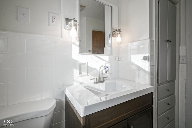 bathroom featuring vanity, toilet, and tile walls