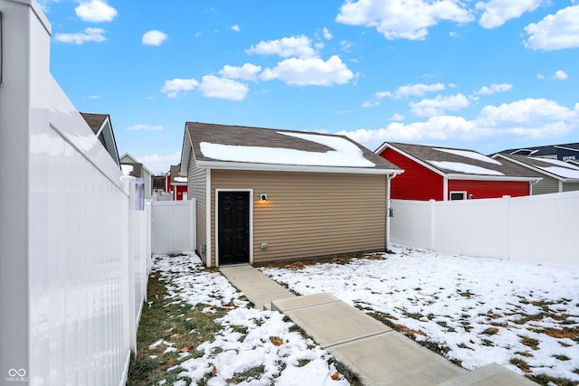 snow covered rear of property featuring an outdoor structure