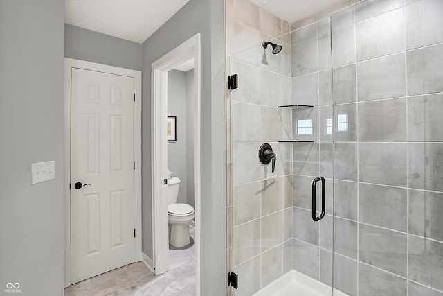 bathroom with a shower with shower door and toilet