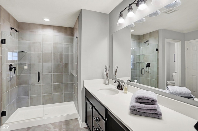 bathroom with vanity, a shower with shower door, and toilet