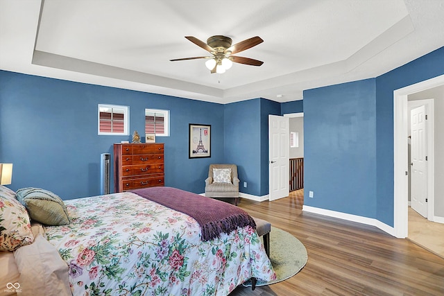 bedroom featuring dark wood-type flooring, ceiling fan, and a tray ceiling