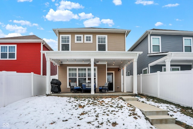 snow covered rear of property with a patio area