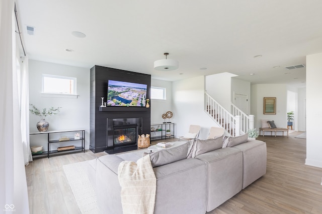 living room with light hardwood / wood-style flooring and a large fireplace