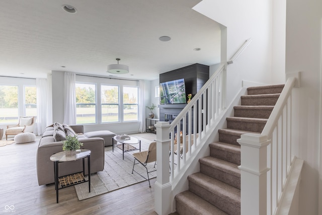 staircase with a large fireplace and wood-type flooring