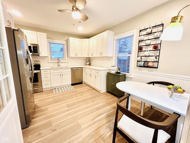 kitchen with sink, light hardwood / wood-style flooring, stainless steel appliances, decorative backsplash, and white cabinets