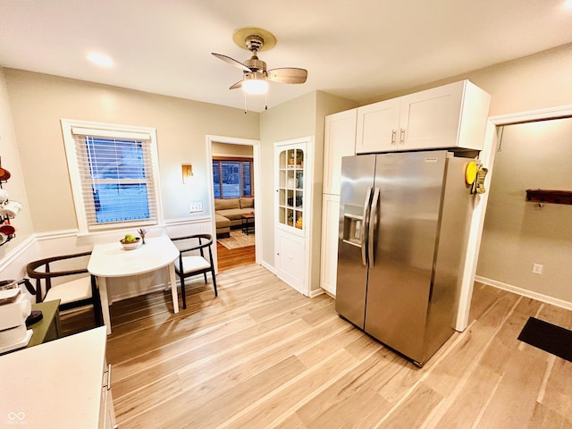 kitchen featuring ceiling fan, stainless steel fridge, light hardwood / wood-style flooring, and white cabinets