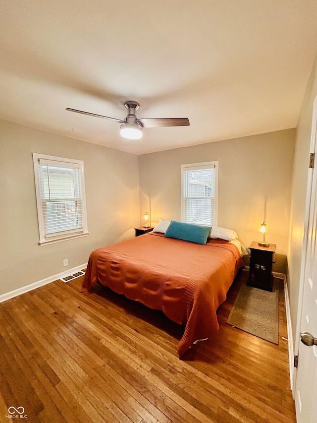 bedroom with multiple windows, wood-type flooring, and ceiling fan