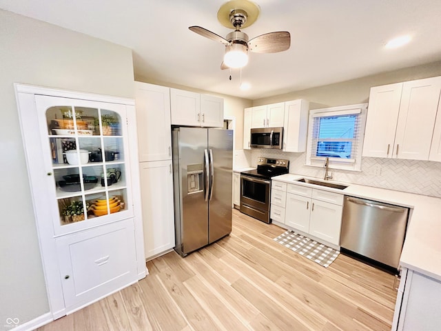 kitchen with sink, tasteful backsplash, appliances with stainless steel finishes, light hardwood / wood-style floors, and white cabinets