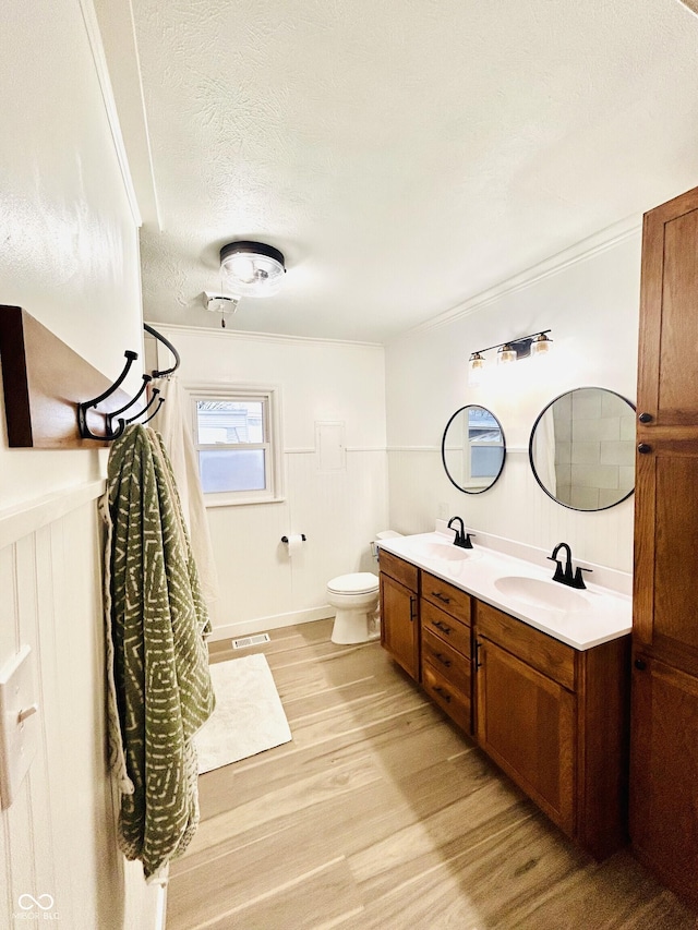 bathroom featuring toilet, crown molding, wood-type flooring, a textured ceiling, and vanity