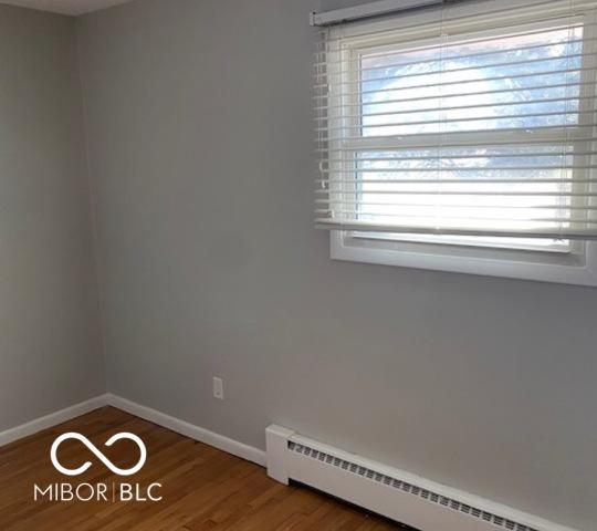 spare room with wood-type flooring and a baseboard heating unit