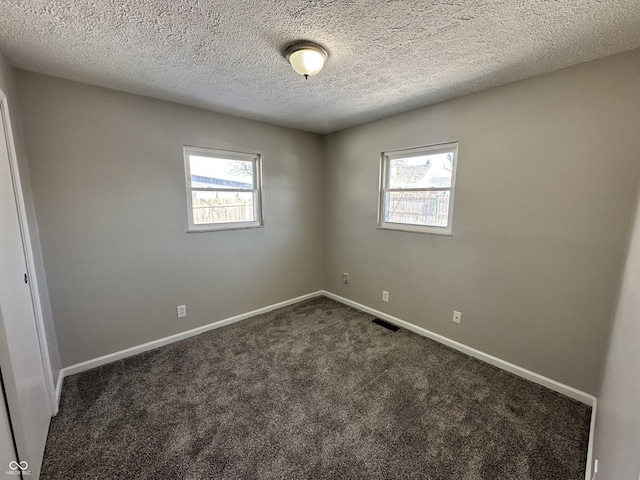 empty room featuring dark colored carpet and a textured ceiling