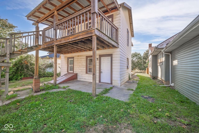 rear view of house featuring a deck, a patio area, and a lawn