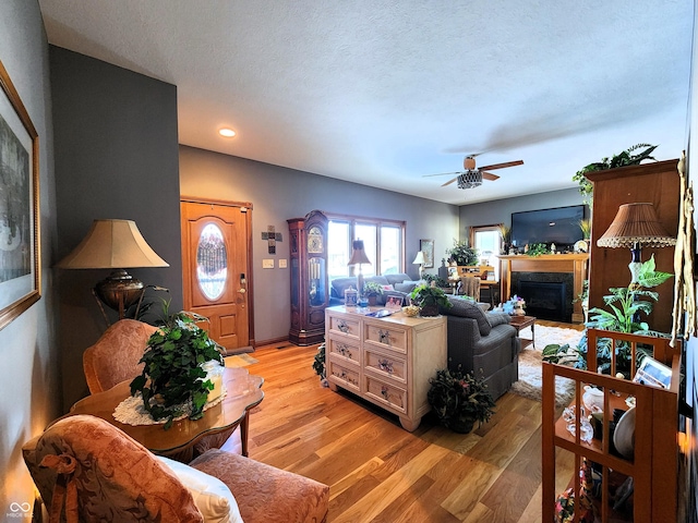 living room featuring ceiling fan, a textured ceiling, and light hardwood / wood-style floors