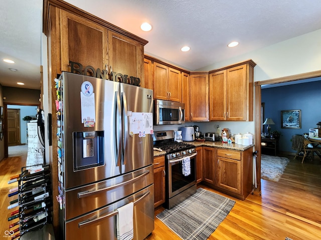 kitchen featuring light stone countertops, light hardwood / wood-style flooring, and stainless steel appliances