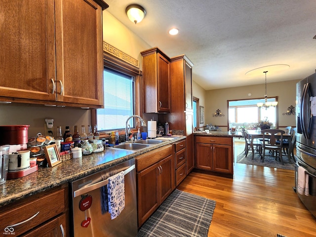 kitchen featuring appliances with stainless steel finishes, sink, hanging light fixtures, a notable chandelier, and light hardwood / wood-style floors