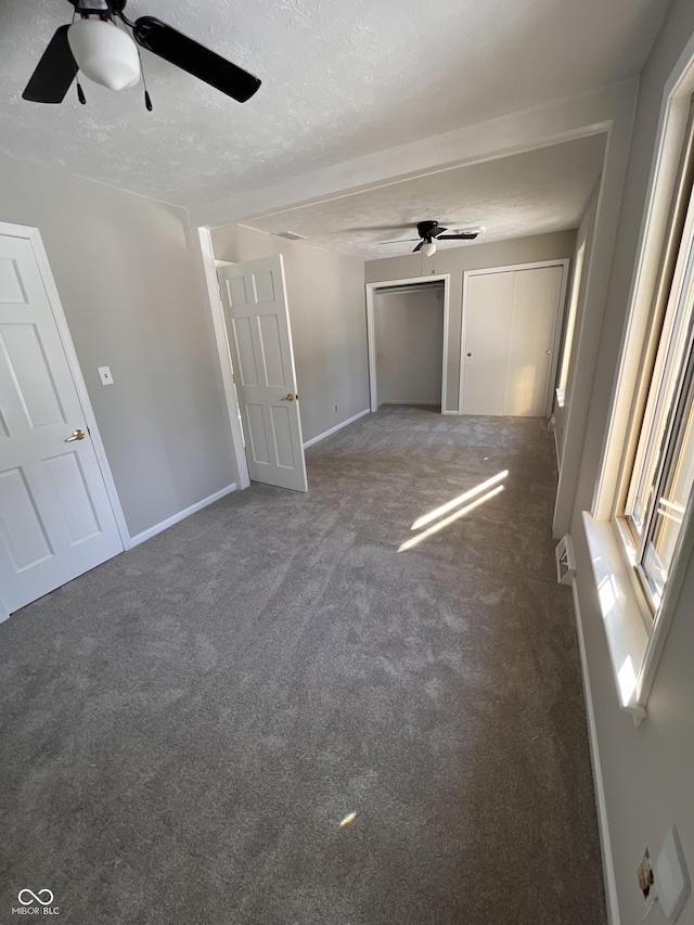 unfurnished bedroom with dark colored carpet, a textured ceiling, and ceiling fan