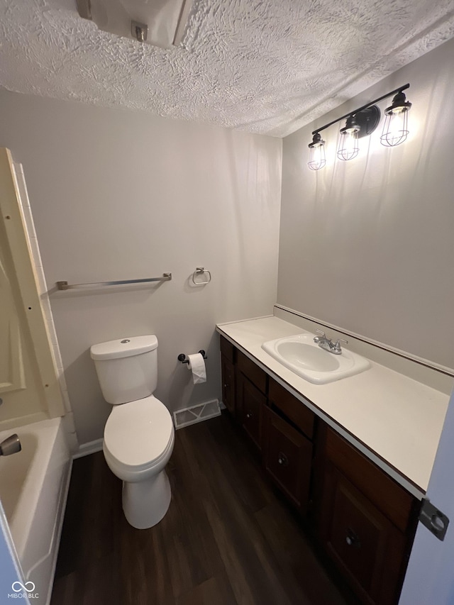 bathroom featuring hardwood / wood-style floors, a bathtub, vanity, toilet, and a textured ceiling