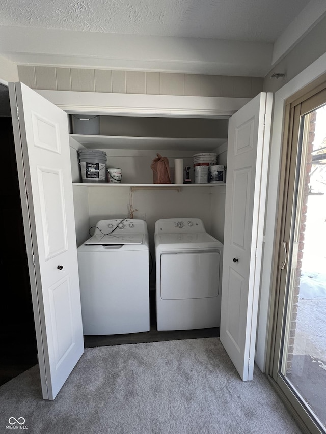 clothes washing area featuring separate washer and dryer, carpet floors, and a textured ceiling