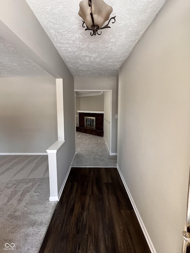 hall with dark wood-type flooring and a textured ceiling