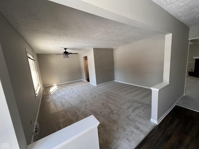 unfurnished living room with dark colored carpet, ceiling fan, and a textured ceiling