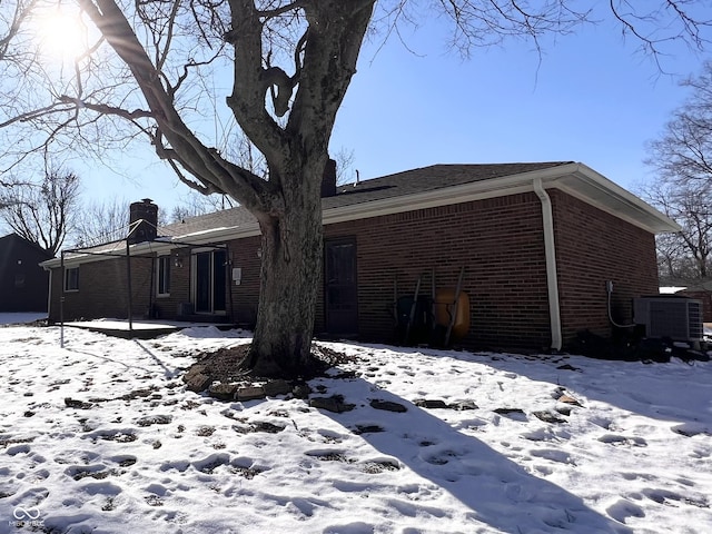 snow covered house featuring cooling unit