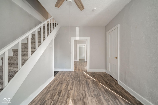 stairway featuring ceiling fan, hardwood / wood-style floors, and a textured ceiling