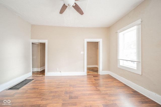 spare room with ceiling fan, wood-type flooring, and a healthy amount of sunlight