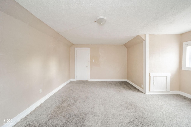 bonus room featuring vaulted ceiling, a textured ceiling, and carpet flooring