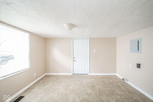 spare room with electric panel and a textured ceiling