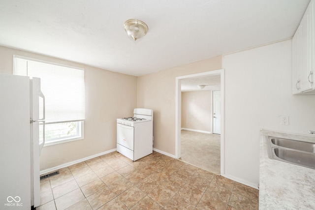 kitchen with white cabinetry, white appliances, and sink