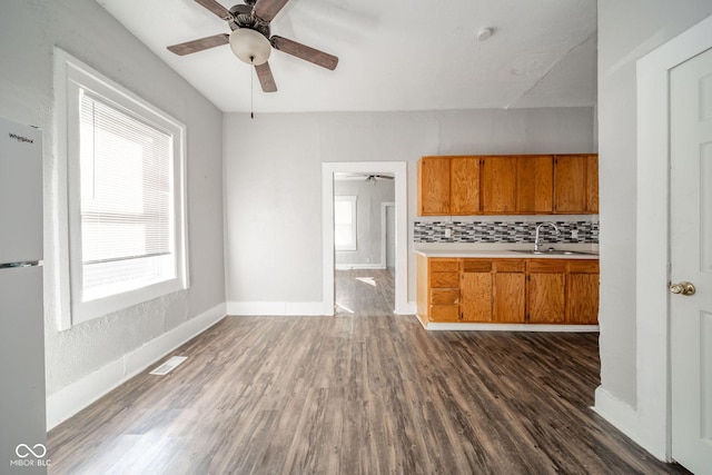 kitchen featuring sink, dark hardwood / wood-style flooring, decorative backsplash, white fridge, and ceiling fan