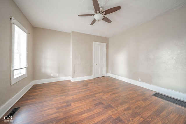 unfurnished room with ceiling fan, a wealth of natural light, a textured ceiling, and dark hardwood / wood-style flooring