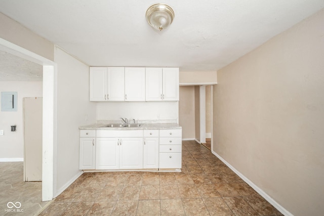 kitchen with electric panel, sink, and white cabinets