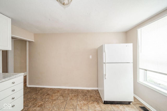 kitchen with white refrigerator and white cabinetry