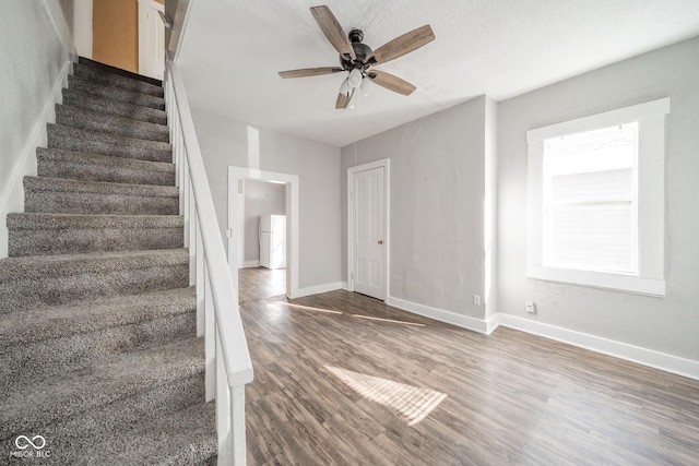 staircase featuring wood-type flooring and ceiling fan