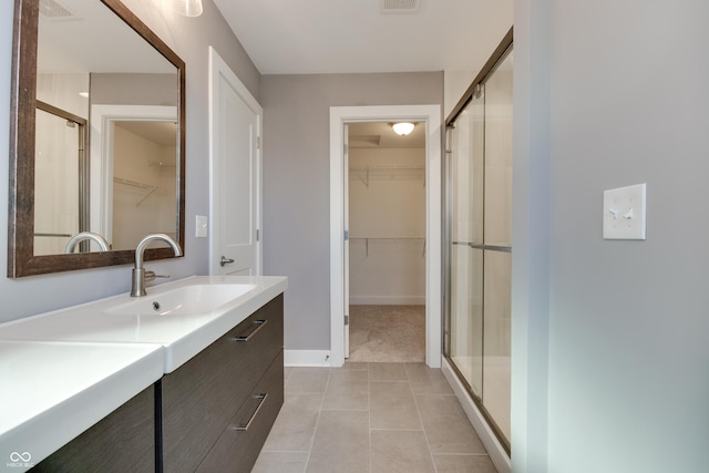 bathroom with tile patterned floors, a shower with door, and vanity