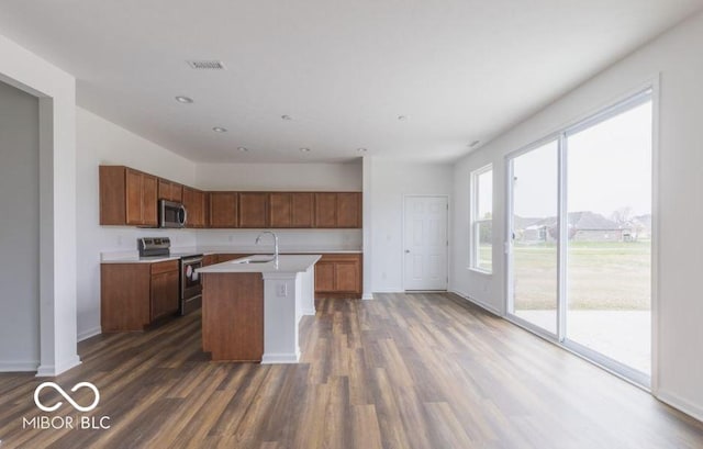 kitchen featuring sink, appliances with stainless steel finishes, dark hardwood / wood-style flooring, and a kitchen island with sink