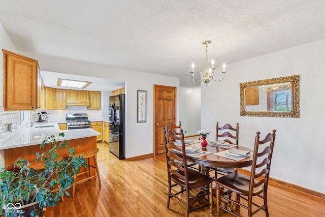 dining space featuring an inviting chandelier, sink, light hardwood / wood-style floors, and a textured ceiling