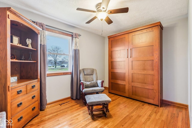 sitting room featuring ceiling fan, light hardwood / wood-style flooring, and a textured ceiling