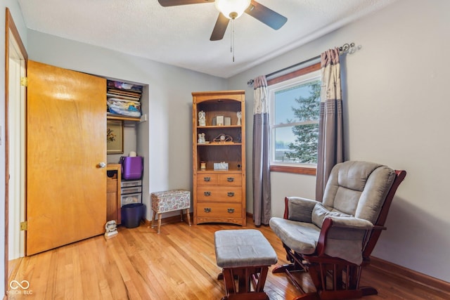 sitting room with hardwood / wood-style floors, a textured ceiling, and ceiling fan