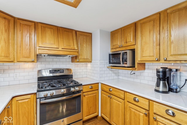 kitchen featuring stainless steel appliances, ventilation hood, and decorative backsplash